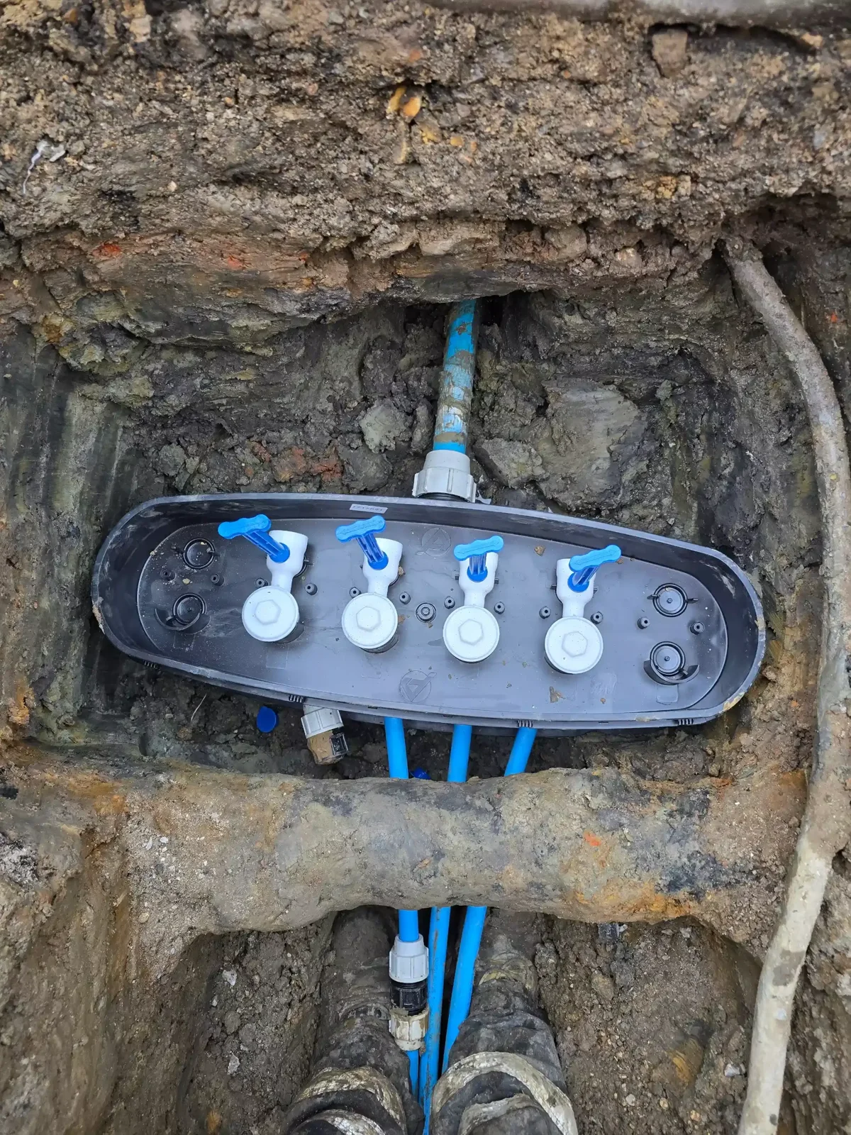 Water supply manifold and blue pipe connections in an excavation