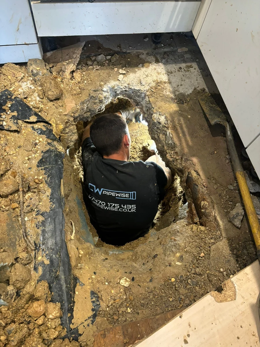 CW Pipewise engineer working on exposed pipework below a floor