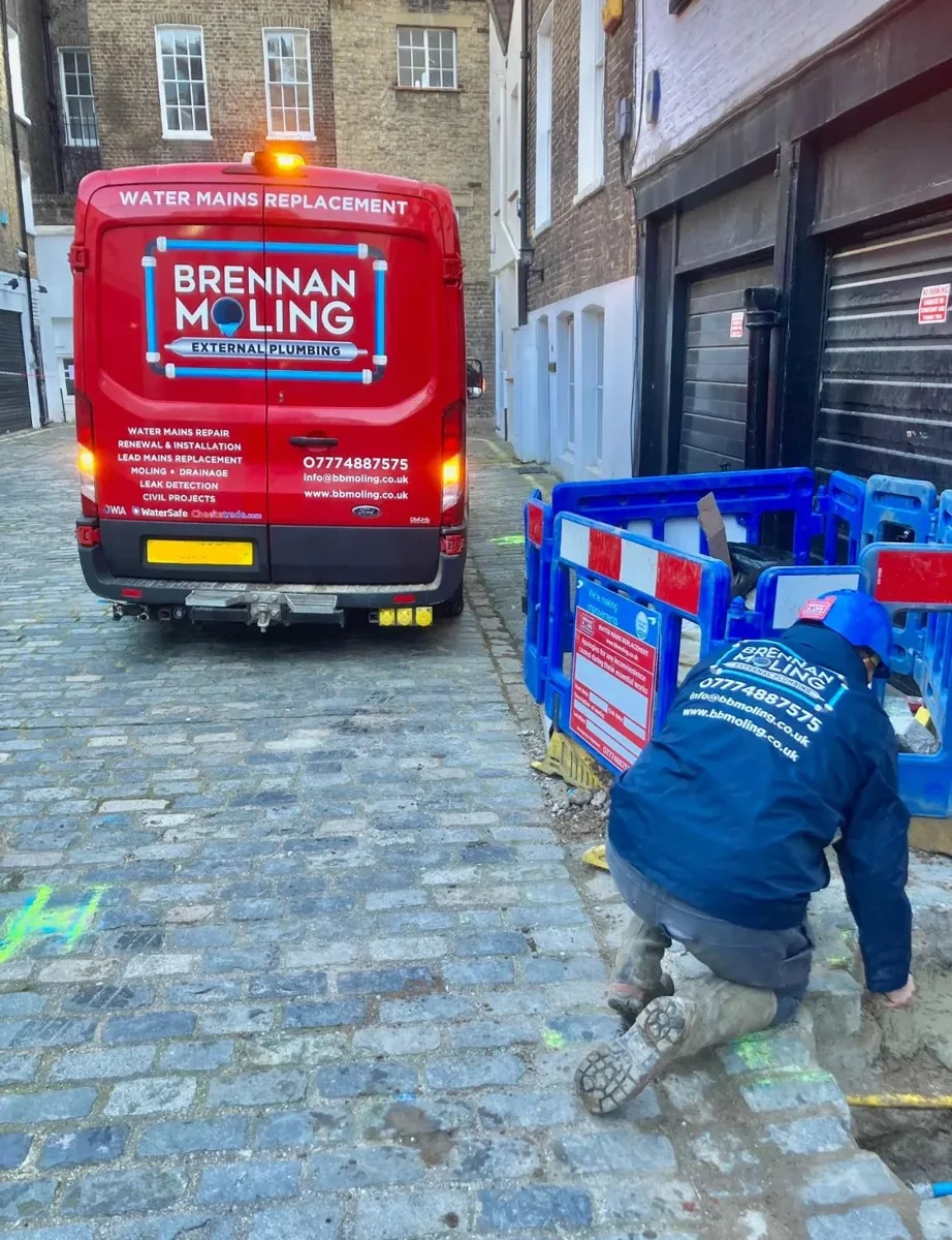 An engineer working beside a barriered access area on a narrow street.
