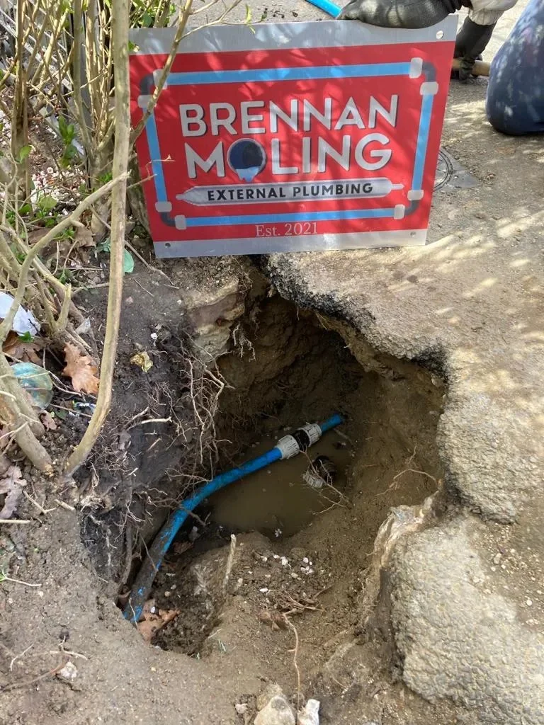 Brennan’s work sign beside an exposed supply-pipe connection.