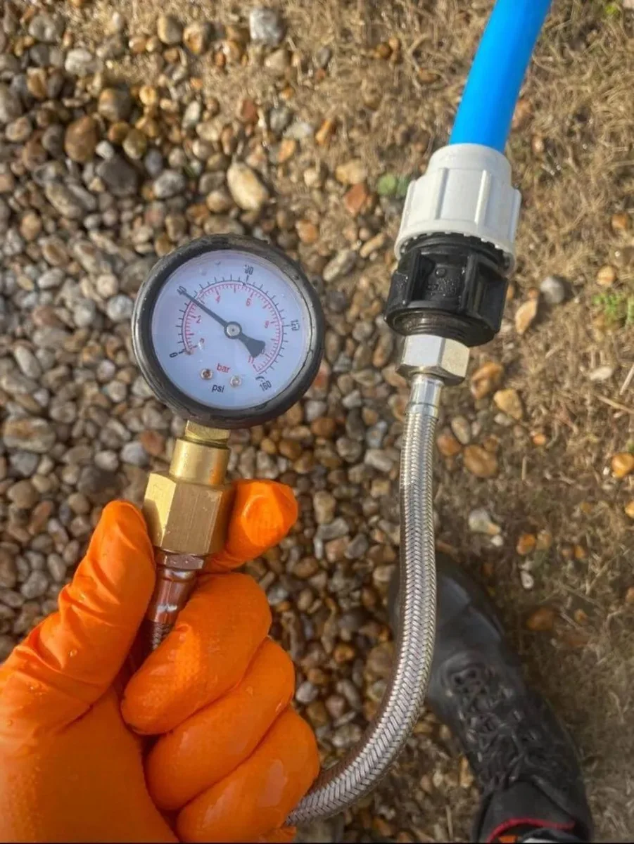 A pressure gauge connected to a blue supply pipe.