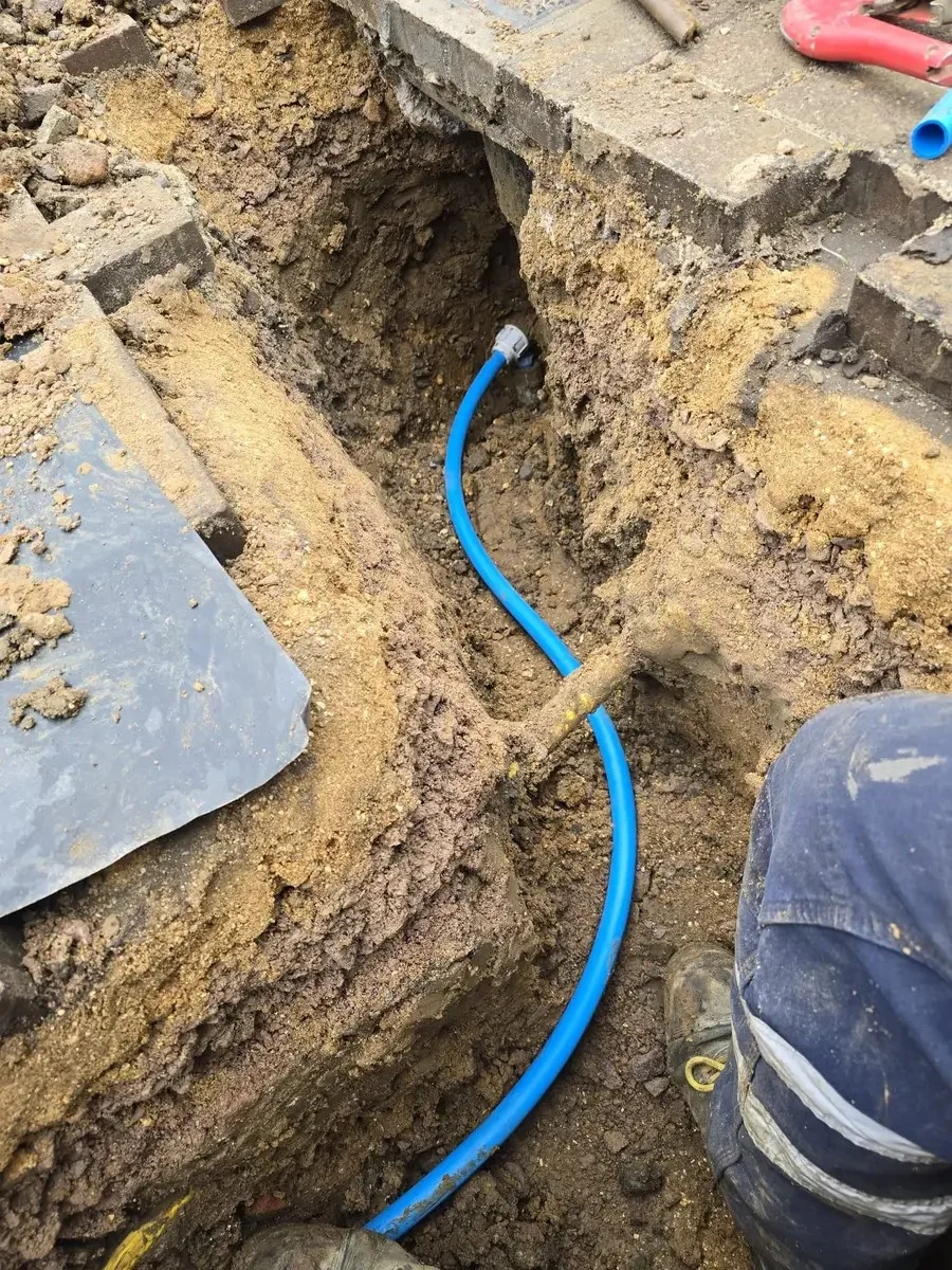 Blue supply pipework within an opened section of driveway.