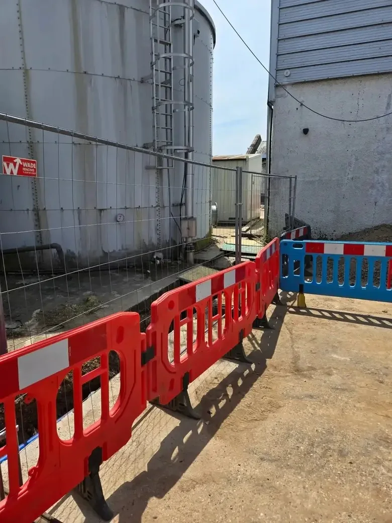 A barriered excavation beside large external tanks.