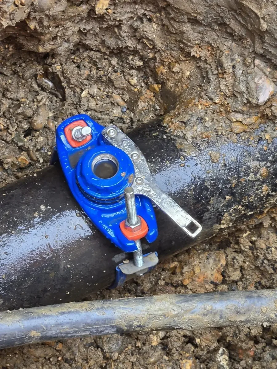 A tapping saddle fitted around an exposed water main.