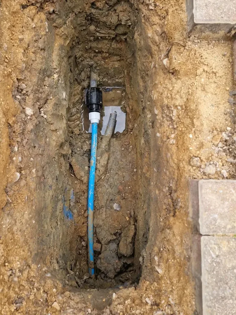 A new blue supply pipe alongside an existing pipe within a trench.