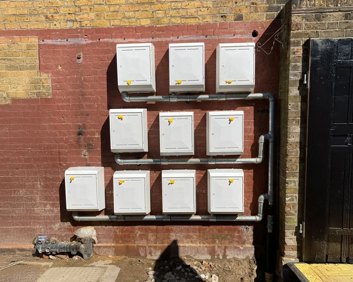 A bank of wall-mounted service boxes with associated pipework.
