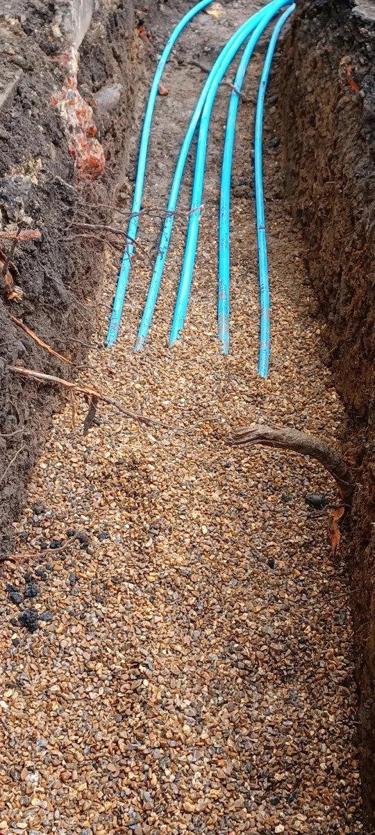 Blue supply pipes laid along an excavated route.