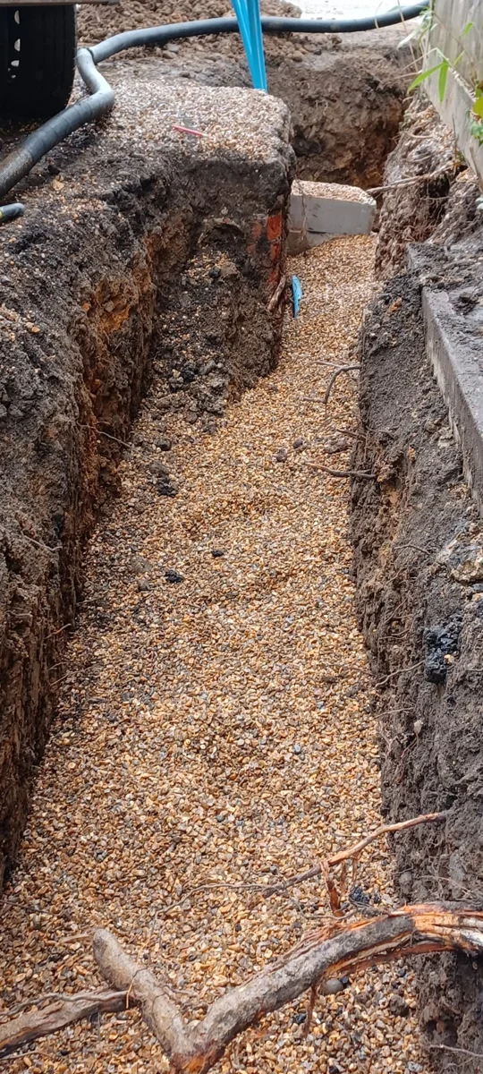 An excavated route with granular bedding prepared along its base.