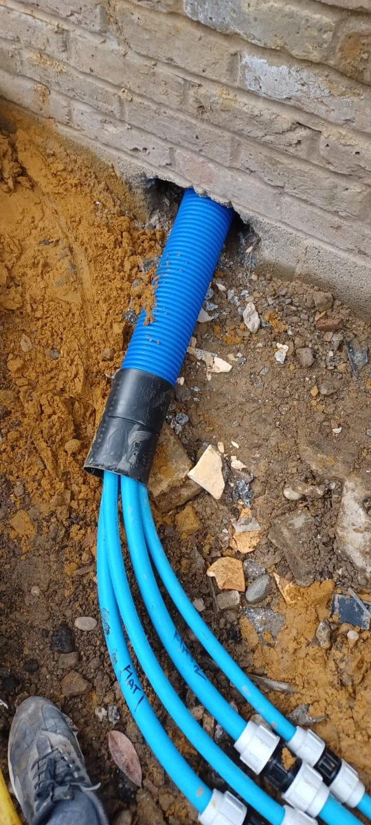 Several blue supply pipes connected within a localised excavation.