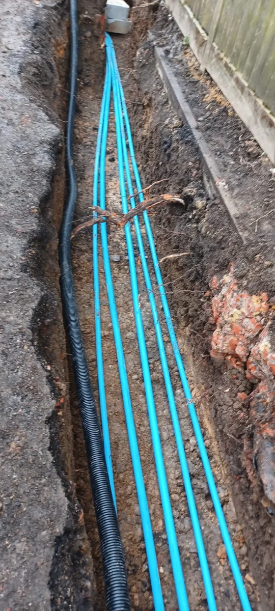 Several blue supply pipes laid along a narrow trench.