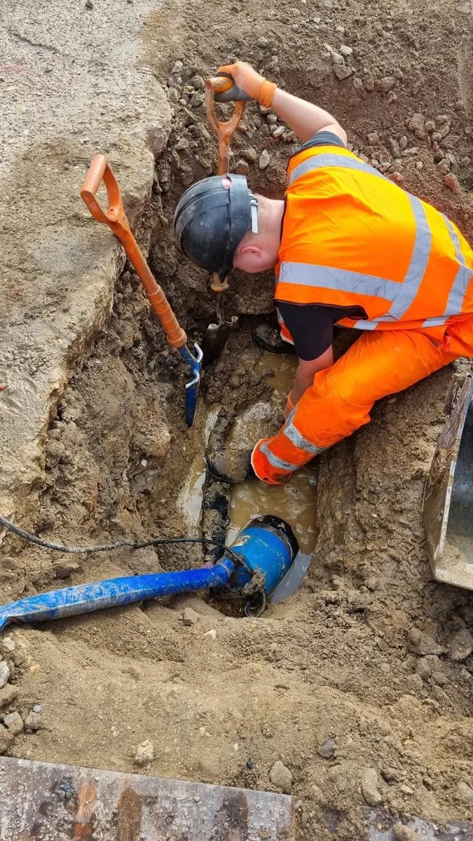 An engineer working beside an exposed main and blue connection.
