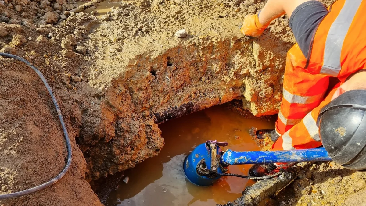 A blue fitting and valve arrangement photographed on an exposed main.