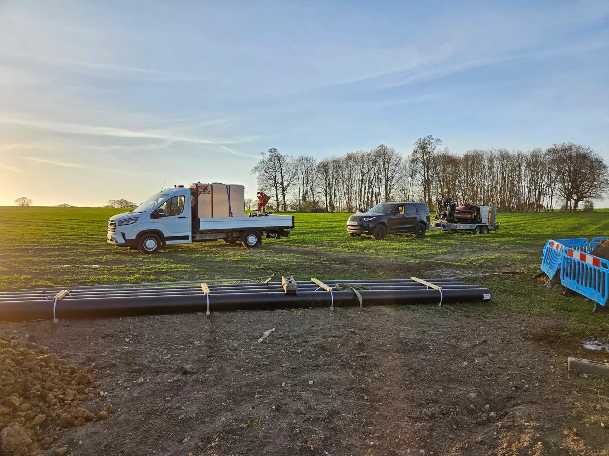 Pipework and installation vehicles at an open site.