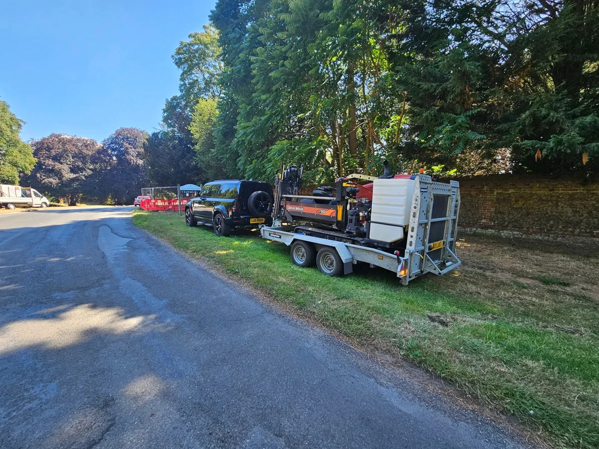 Specialist vehicles and equipment parked along a tree-lined road.