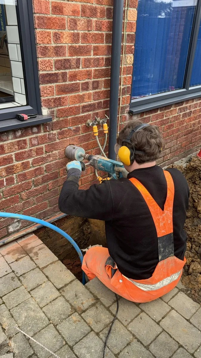 An engineer working on pipework at an external wall.