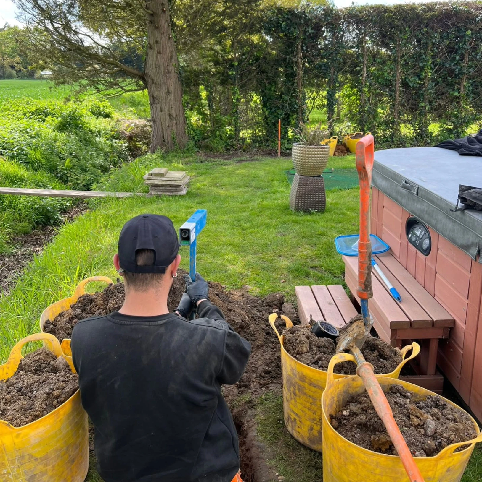 Engineer checking alignment for a moling route through a garden